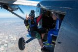 A videographer hangs from the door of the Twin Otter in flight.