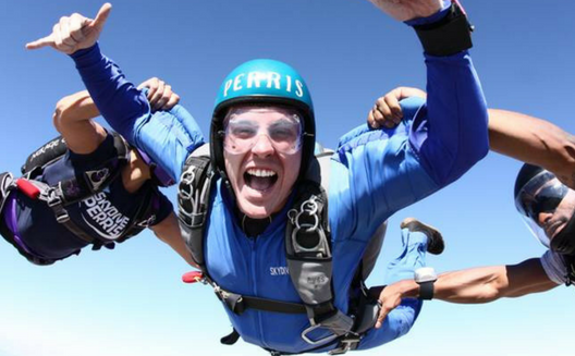 Two people assist a skydiver.